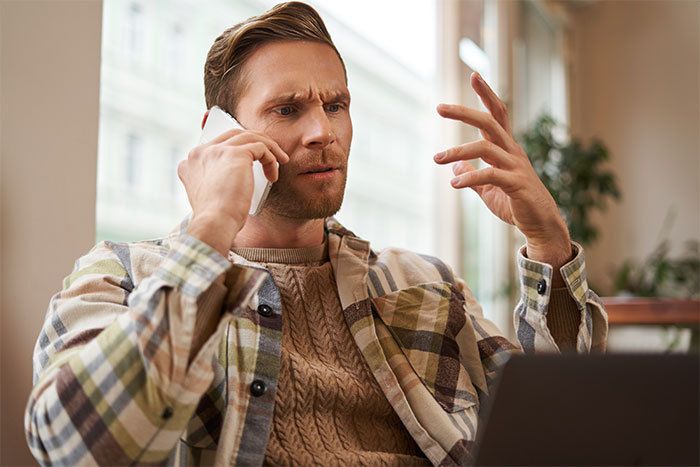 Man looking frustrated while talking on phone, possibly discussing feeding nieces junk food for several days.