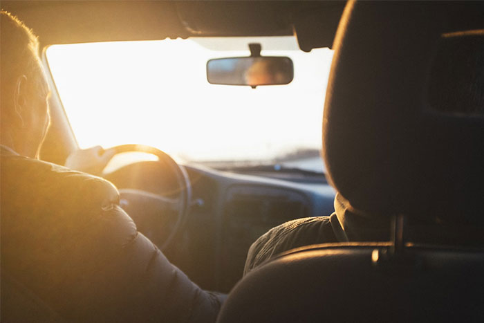 Couple sitting in a car at sunset, illustrating a woman bearing the physical consequences of an accident caused by her fiancé.