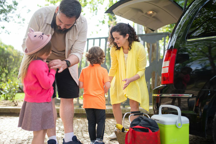 Family preparing for a trip outside near a car, illustrating a woman refusing to take sister’s kid on trips situation.